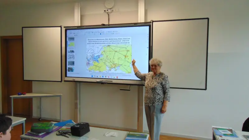 Zeitzeugin Frau Zerr an der digitalen Tafel im Klassenzimmer