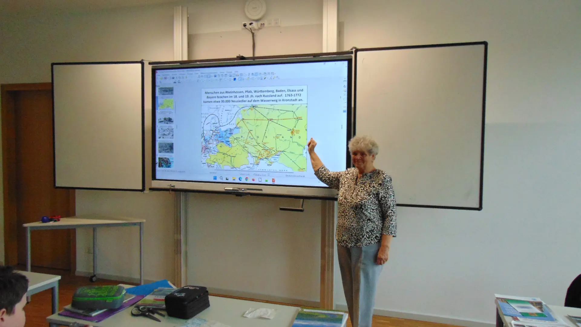 Zeitzeugin Frau Zerr an der digitalen Tafel im Klassenzimmer